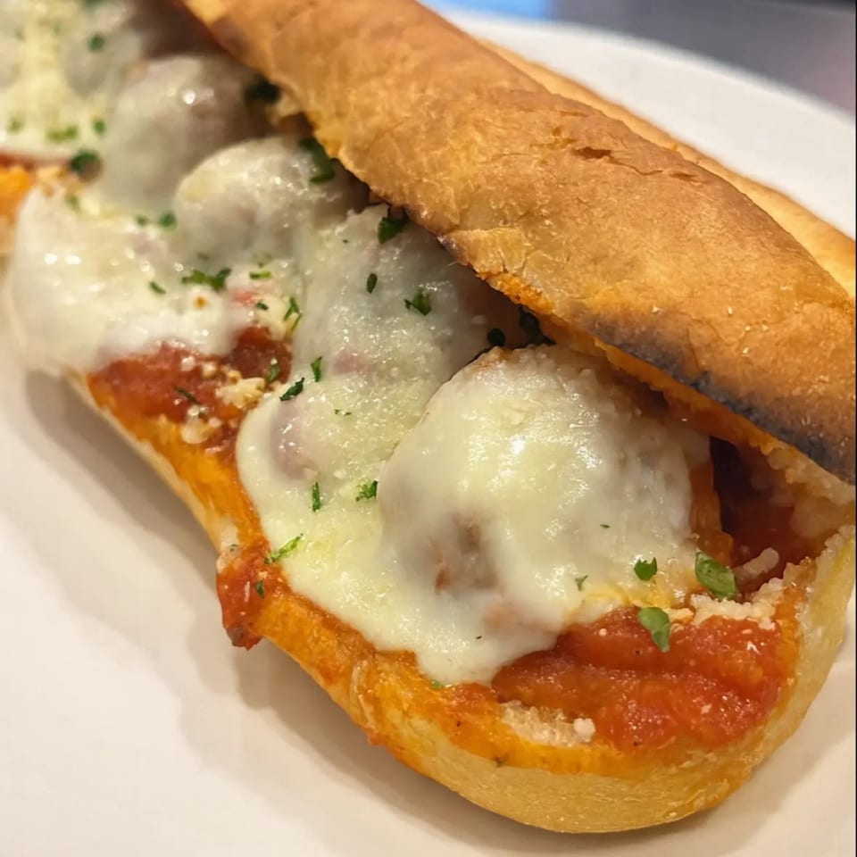 Amore Pizza & Subs meatball sub with melted mozzarella cheese, marinara sauce, and parsley.