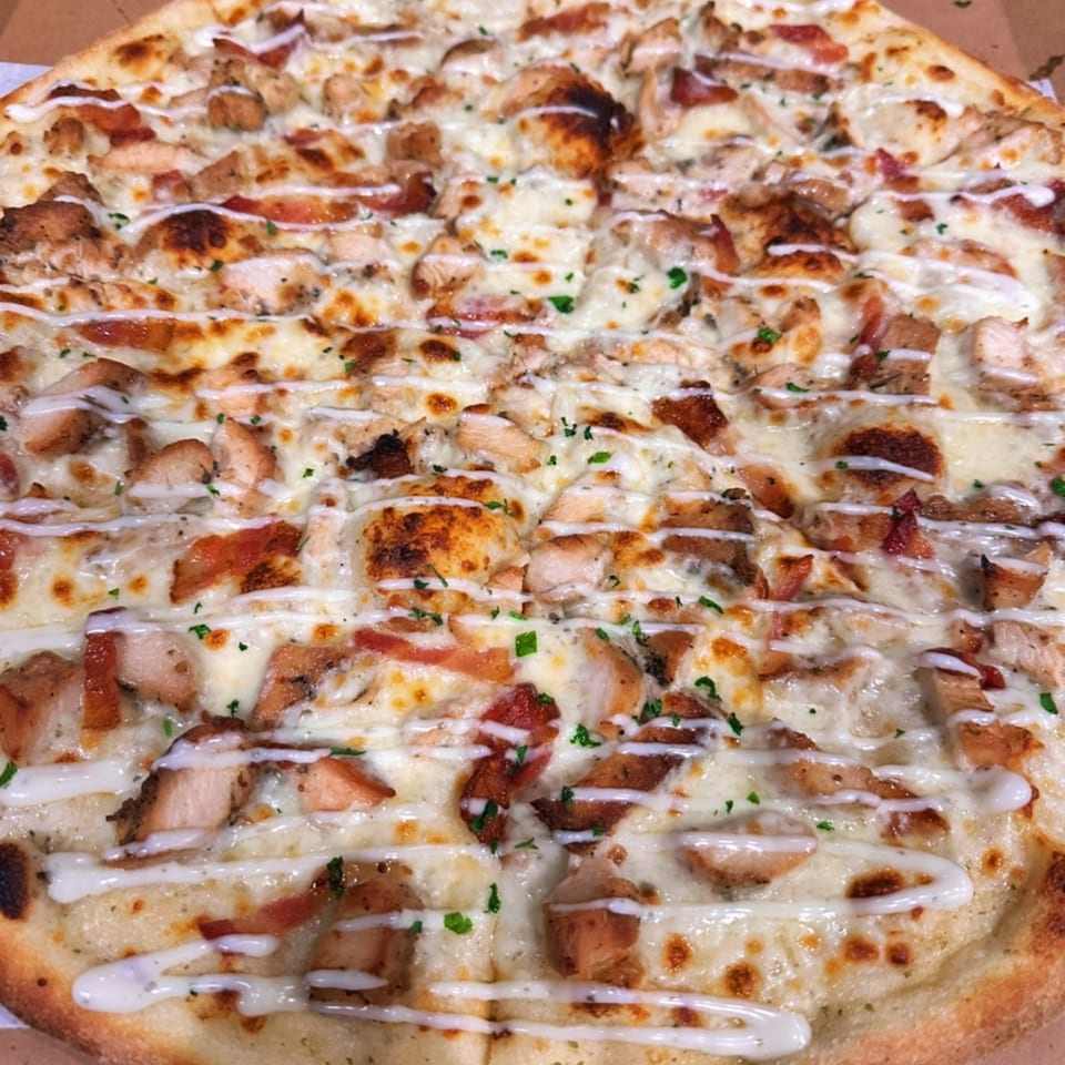 Amore Pizza & Subs' chicken bacon ranch pizza, topped with melted cheese, chicken, bacon, and ranch drizzle.
