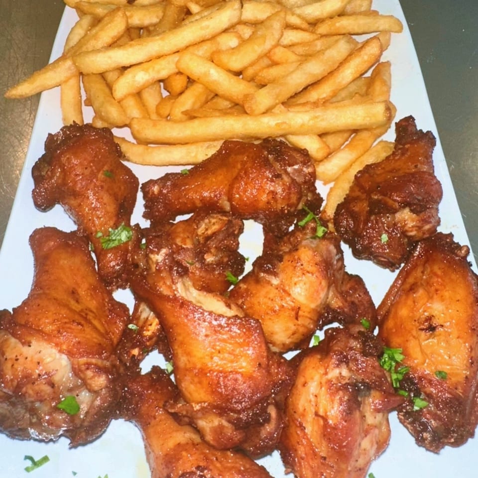 A plate of Amore Pizza & Subs' crispy chicken wings and golden french fries.
